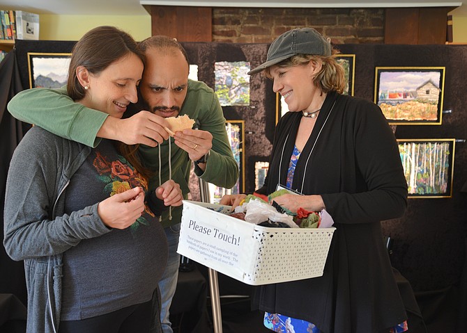 Soroush Parsa (center) is fascinated by the many textures of the papers that artist Ronni Jolles, right, sources from around the world and employs in her work, while Moara Parsa looks on.
