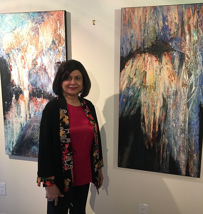 Potomac artist Nimi Trehan stands before two paintings inspired by a visit to Luray Caverns.
