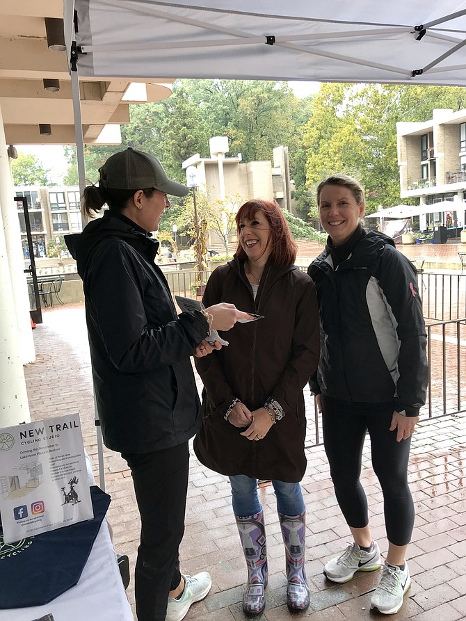 Liz Kamp, owner and instructor of New Trail Cycling Studio at Lake Anne Plaza, talks with Beth Davis of Oakton and Susan Snyder of Potomac Falls on Saturday, Oct. 29 during the new Harvest Festival.