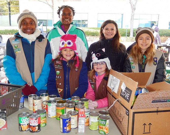 Sorting canned goods last year with Girl Scout Troop 3327 of Chantilly are (back row, from left) Brianna Mosely, mom Tanesha Mosely, Jeanine Blomberg and Ruth Moran, and (front row, from left) sisters Morgan and Phoebe Blomberg. 
