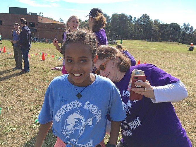 Students, preschool through sixth grade, are given grade-specific colored t-shirts to have their laps marked on. The t-shirt has 25 laps as the goal. SLES Principal Dr. Maureen Marshall marks fifth grader Edom Birhane's t-shirt.