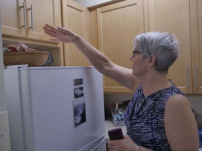 Mary MacCarthy points to the new kitchen cabinets in her renovated apartment at Culpepper Garden.