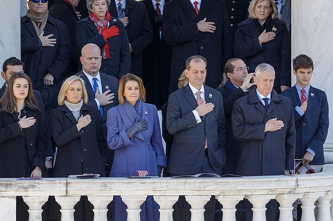 House Minority Leader Nancy Pelosi, center,  flanked by Homeland Security Secretary Kirstjen Nielsen and Department of Labor Secretary Alexander Acosta, places her hand over her heart during the playing of the National Anthem during the National Veterans Day Observance at the Memorial Amphitheater Nov. 11 at Arlington National Cemetery.