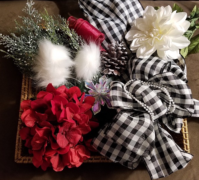 A mixture of dark red and white flowers along with holiday greenery and black and white ribbon are elements that designer Mary Biletnikoff will use to create a wreath for Light Up the Season.