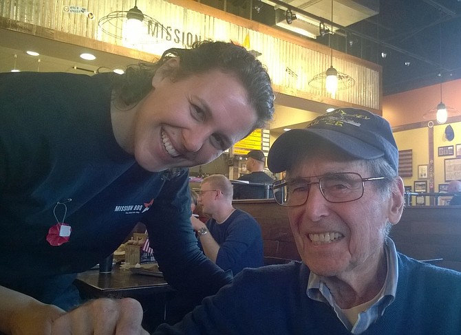 Elizabeth McGuirk, regional community ambassador of MISSION BBQ, celebrates World War II serviceman and loyal restaurant patron, Sigmond Alman of Oakton, Sunday at the chain’s Chantilly restaurant. The 93-year-old veteran was a radar operator for the U.S. Navy aboard the light aircraft carrier USS Monterey — the same ship to which an officer named Gerald R. Ford was assigned, long before he became the 38th president of the United States and commander in chief.