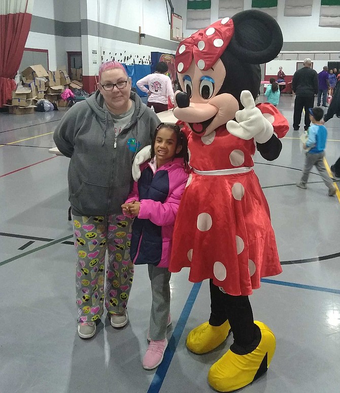 Malia Dixon, center, poses in her new coat with her mother Jessica Wehrman and Minnie Mouse at the annual Firefighters and Friends coat drive distribution Oct. 27 at the Leonard Armstrong Recreation Center.