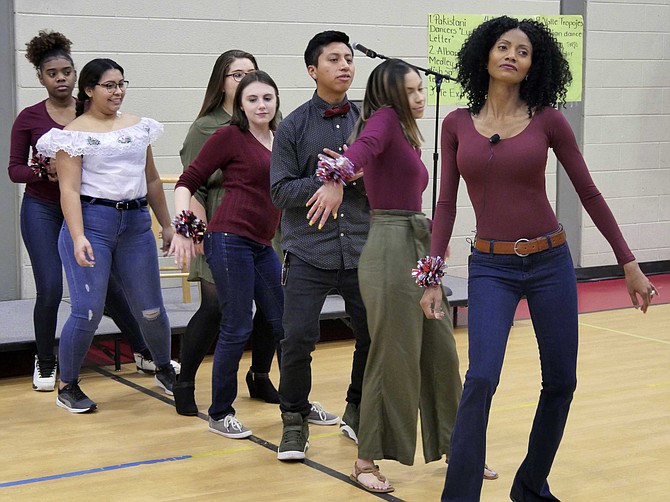 This year's traditional Thanksgiving dinner has been energized with entertainment organized by Lashawn Grace, an English teacher at Langston-Brown Continuation Program. She leads a group of students in a synchronized dance and then reaches out into the audience for partners.