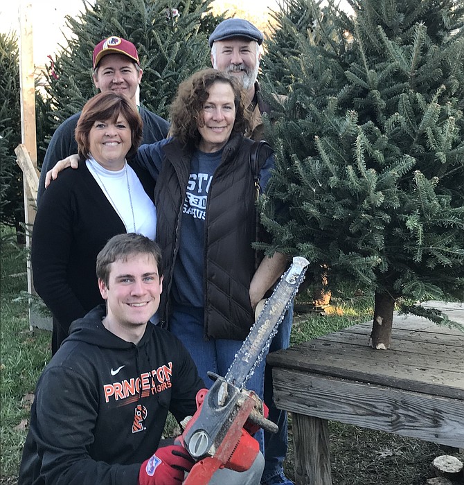 Paul and Karen Novak of Herndon (far left) purchase their annual Christmas tree one more time at the 'Elvis Tree Lot,' corner of Elden and Center Streets in Herndon. Richie Smiechowski, 18, of Herndon holds his chainsaw while Michael Hum of Herndon and Suzanne Eaton, who operates the lot, enjoy the moment too.