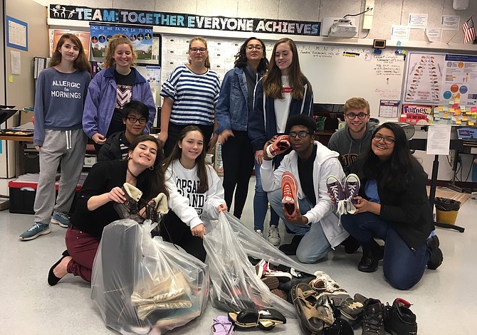 Members of the MVHS Vocal Recall advanced choir bag shoes collected from the drive: From left, back row, Nicole Duchaine, Annie Hood, Yara Ammar, Melanie Palacios Beltran and Casey Zanowic; middle row, Mark Rivera and Zachariah Pifer; front row, Erica Bartell, Laura Schmechel, Denilson Zapata, and Gopika Patel.