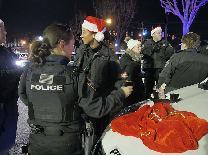 Officer Lillian Hammond hands out donated stuffed toys and candy canes to the children bringing a toy at the Fill the Cruiser Holiday Toy Drive at Lee Harrison Shopping Center.