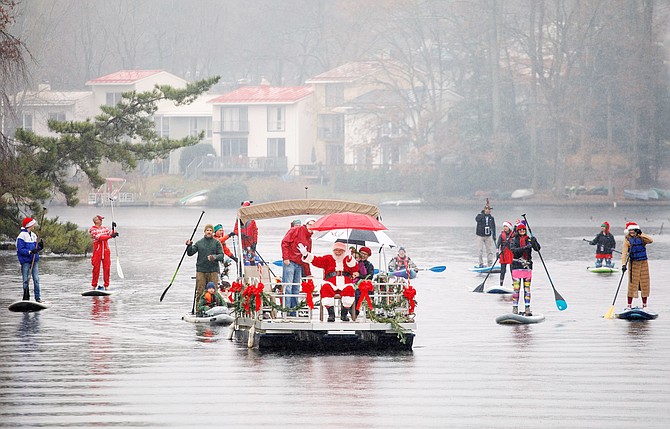 Santa is escorted by an entourage of his best paddleboard elves as he prepares to dock at Lake Anne Plaza in Reston for the highly anticipated “Jingle on the Lake” produced by Lake Anne Merchants.