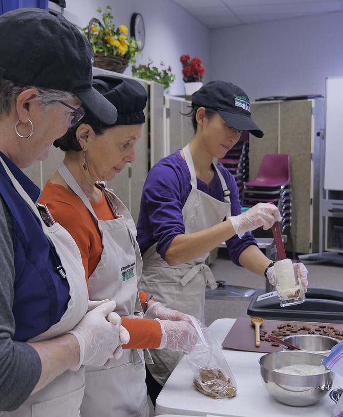 Cyndi Gadhia layers a glass with gingersnap crumbs, yogurt, pears and crystallized ginger to make a healthy and nutritious but delicious holiday trifle. She is assisting Master Food Volunteers Caryn Wagner and Nancy Broff with the demonstration at Langston Community Center.