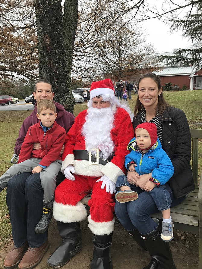Jeremy Sontag of Oak Hill holds his son Ethan, 4½, as his wife Jennifer holds son Owen, 1½. Together they sit beside a tractor-driving Santa at Fairfax County's ‘Christmas at the Farm’ held at Frying Pan Farm Park in Herndon Dec. 2, 2018.
