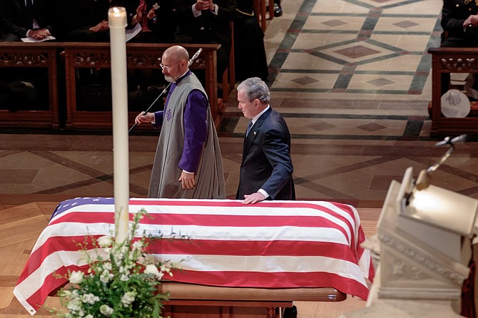 Former president George W. Bush lays his hand on the flag-draped casket of his father, George H.W. Bush, after delivering the eulogy at the state funeral service for the 41st president Dec. 5 at Washington National Cathedral.
