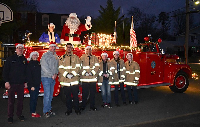 The Vienna Volunteer Fire Department members pose with their prized possession, a 1946 fire truck, as it carries Santa through Vienna neighborhoods.