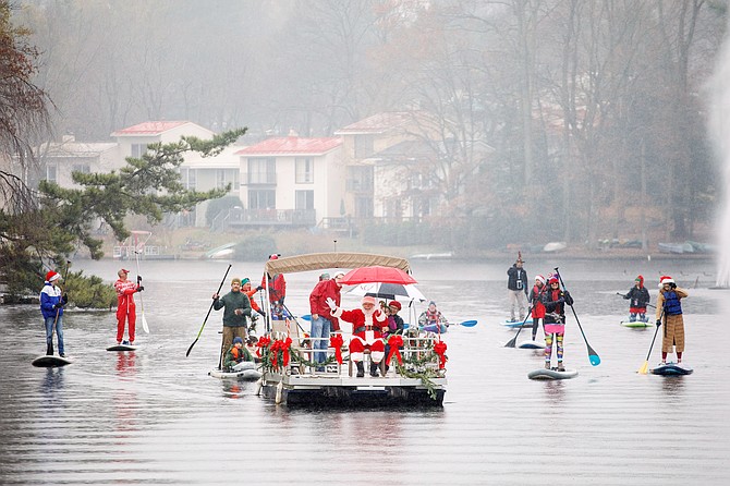 Sharing Holiday Spirit: Santa is escorted by an entourage of his paddleboard elves as he prepares to dock at Lake Anne Plaza in Reston for Jingle on the Lake on Dec. 1, 2018. The pages of the Connection Newspapers have been full of holiday spirit, beginning before Thanksgiving.