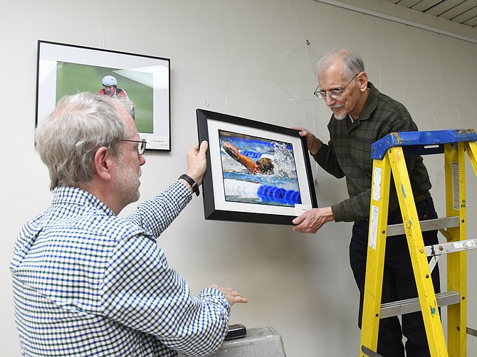 RSVP Northern Virginia volunteer photographers George Bradshaw, right, and John Olsen prepare a special exhibit featuring photos from the 2018 Northern Virginia Senior Olympics, Dec. 13, 2018,  at the Oak Marr RECenter in Oakton.