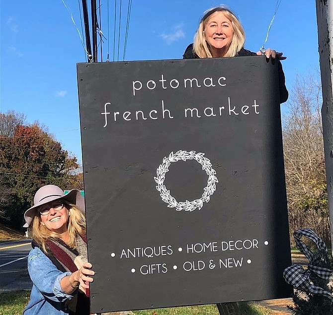 Rene Shaw and Teri Troxell hang the sign in front of their new store on River Road.