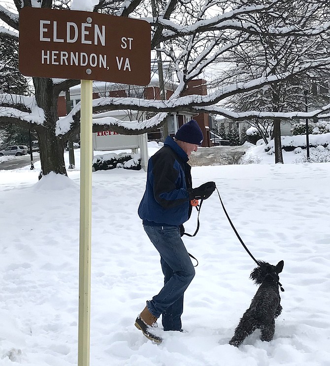 Tom Speirs of the Town of Herndon and his dog, Keira, romp and play in the snow on the Town Green beside the W&OD Trail after the first snowfall of the 2019 season.