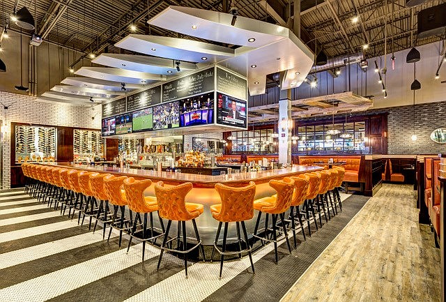 The centrally-located bar features wrap-around stools that are reminiscent of a 1960s design.