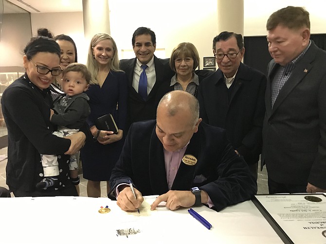 With loved ones looking on, Cesar del Aguila makes history as the first Latino American elected to office in the Town of Herndon and signs his oath of office certificate during the Herndon Town Council 2019-2020 Swearing-In Ceremony held Wednesday, Jan. 9, 2019.