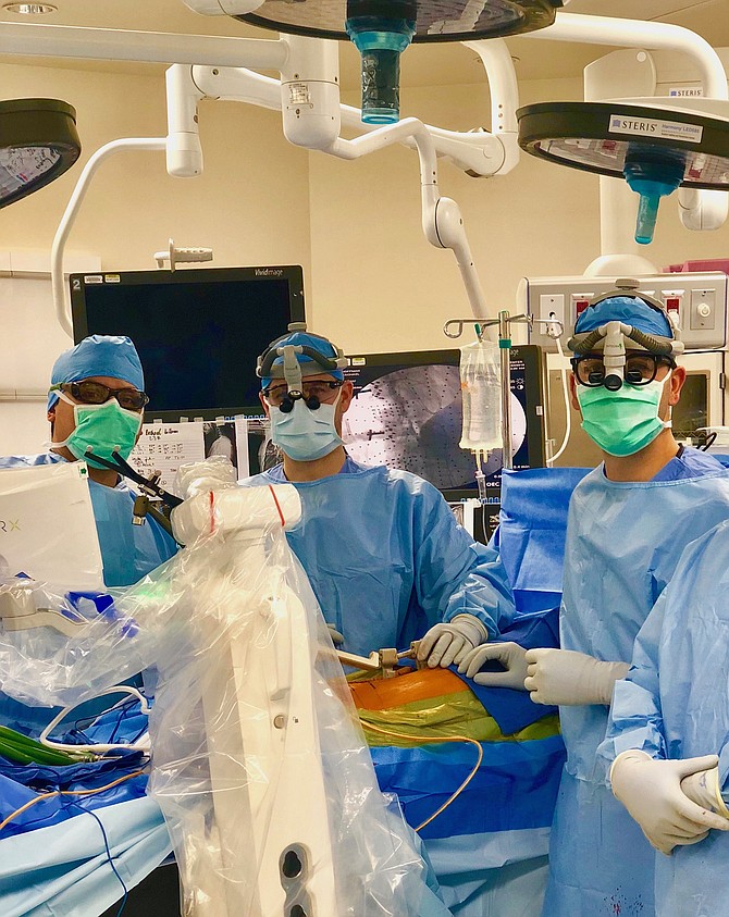 (From left): The Virginia Spine Institute surgical team, Randy Perez, CSTFA, Dr. Christopher Good, and Dr. Colin Haines prepare for the groundbreaking spine surgery offering healing through technology and innovation at Reston Hospital Center (RHC). The hospital and the Virginia Spine Institute are leaders in robotic-assisted technology and procedures in the operating room.