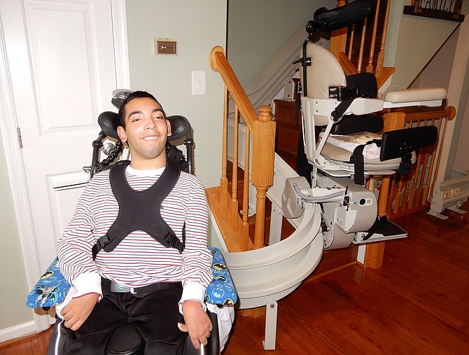 Juwaan Espinal poses beside the chair lift that takes him upstairs to his bedroom via a special rail.