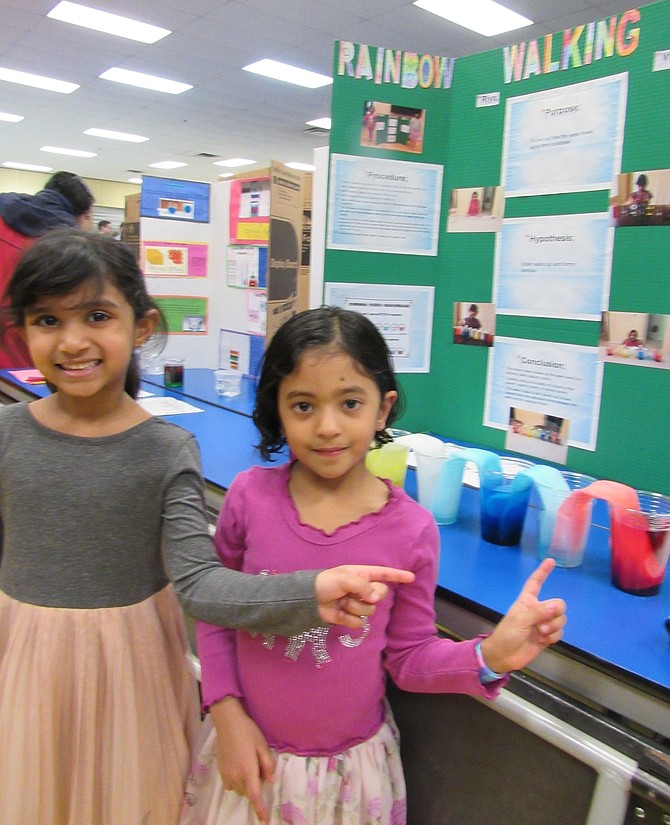 (From left) Riya Nanduri, 5 and Vritika Chilukamarri, 5 of Herndon explain their procedures and the purpose, hypothesis and conclusion for their  Rainbow Walking Water Project.