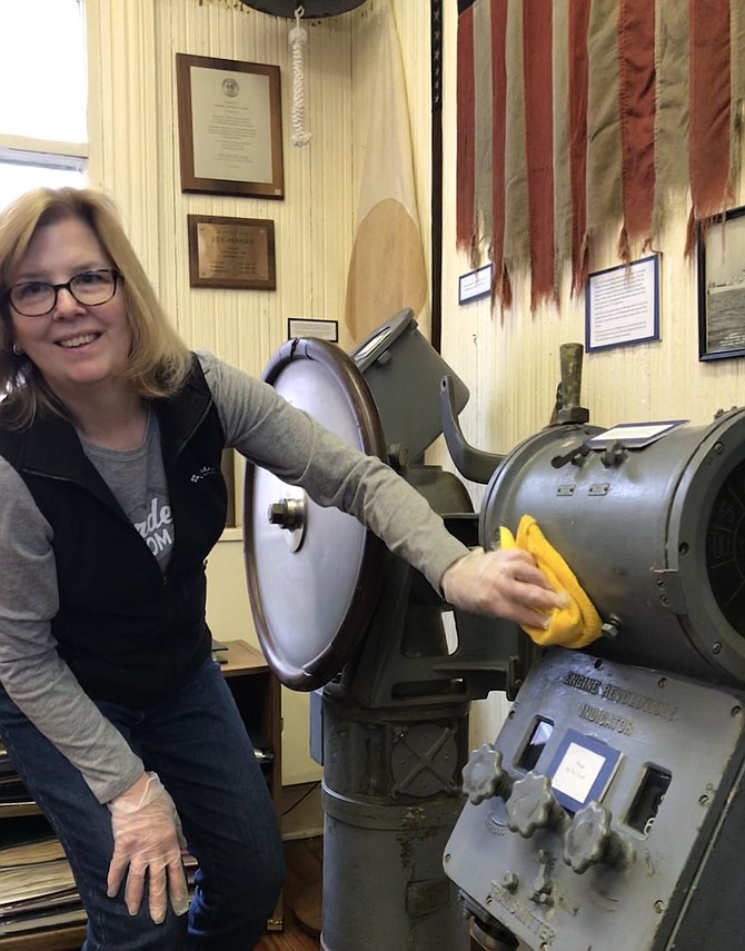 Nancy Saunders, Board President of the Herndon Historical Society, gives artifacts in the Herndon Depot Museum a gentle cleaning.