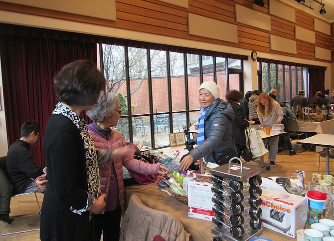 From left, vendors Sumi Gallas of Reston and Yumi Shintani of Herndon help a customer with her selection at Spring Flea Market RCC Hunters Woods.