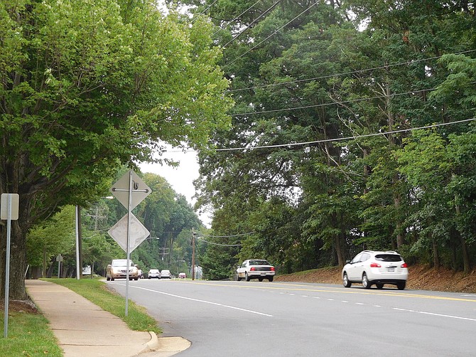 During spring, green trees form a scenic background for vehicles driving on Old Lee Highway.