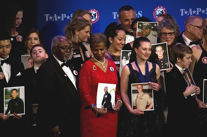 Family members of fallen military veterans hold photos of loved ones at the T.A.P.S Honor Guard Gala March 6 to mark 25 years of the Arlington-based organization’s service to military family survivors.