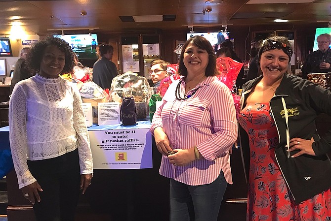 Rock It Grill owner Laura Seiss, center, Hannah Harris and event coordinator Joanna Bellerdine stand in front of the raffle items display at the 30th anniversary celebration of the Old Town karaoke bar and restaurant. The March 31 event served as a fundraiser for the nonprofit Guiding Eyes for the Blind.