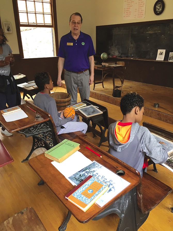 Ralph Buglass explains life in a one-room schoolhouse to Brandon Rosario, 9, and his brother Taylor, 7, at Kingsley School in Clarksburg Sunday.