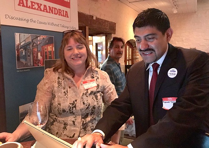 Agenda:Alexandria executive director Donna Walker James, left, watches as Fernando Torrez makes a donation to the organization at an early giving Spring2ACTion Happy Hour April 8 at Union Street Public House.