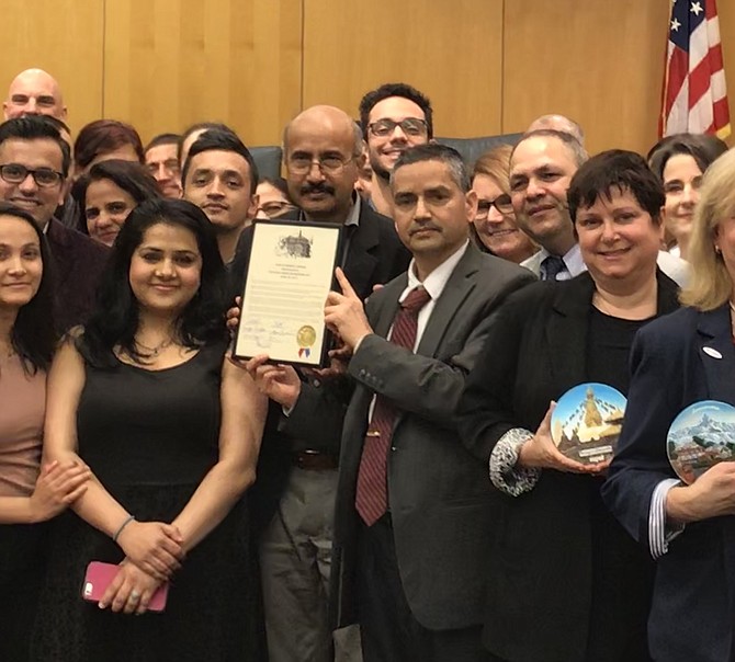Center, Parshuram Bhandari and Arjun Sigdel hold the Town of Herndon Proclamation of Nepalese American Heritage Day April 20, 2019, surrounded by well-wishers at the presentation ceremony held during Herndon Town Council Public Session April 9, 2019.