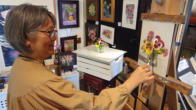 Theresa Miller of Vienna paints a flower; she specializes in oil paintings and watercolors of florals and landscapes.