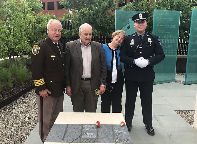 Ginny Obranovich, second from right, rests her head on the shoulder of her son, Officer Robert Hill, after placing a flower at the memorial to her late husband, Corporal Charlie Hill, during the APD Fallen Officers Memorial wreath-laying ceremony May 6 at APD Headquarters. With them are Sheriff Dana Lawhorne and Obranovich’s husband Richard.