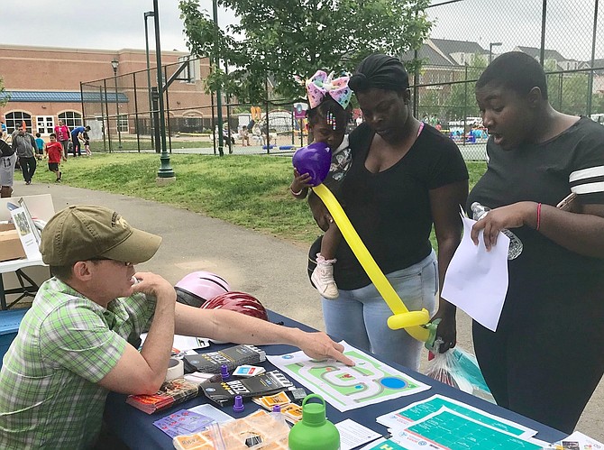 Randy Cole of the City of Alexandria’s bicycle committee explains the local bike routes to Jerusalem Brown, holding baby Jai’lyrik Moore, and Maleah Muskelly.