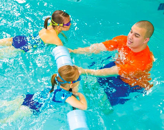 An instructor at Goldfish Swim School teaches young children how to swim. Lessons can help ensure water safety.