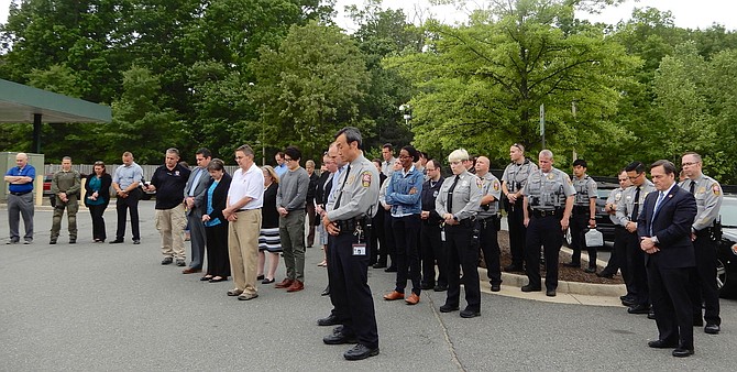 Police officers and others bow their heads during the moment of silence. At far right, in suit, is Deputy County Executive Dave Rohrer.