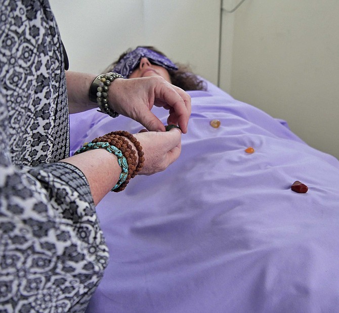 Shaman Deb Heisel begins the ceremony by placing multi-sized and colored stones down the body of her client.
