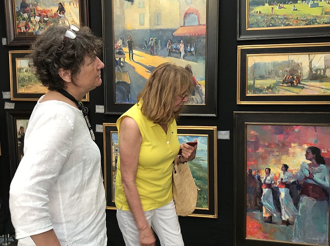 Meg Hill of Reston admires the impressionist oil paintings by award-winning local artist Jill Banks of Fairfax during the 2019 Greater Reston Arts Center Northern Virginia Fine Arts Festival.