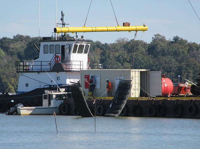 Cranes lower marine material to the river bottom to form the foundation of the breakwater.