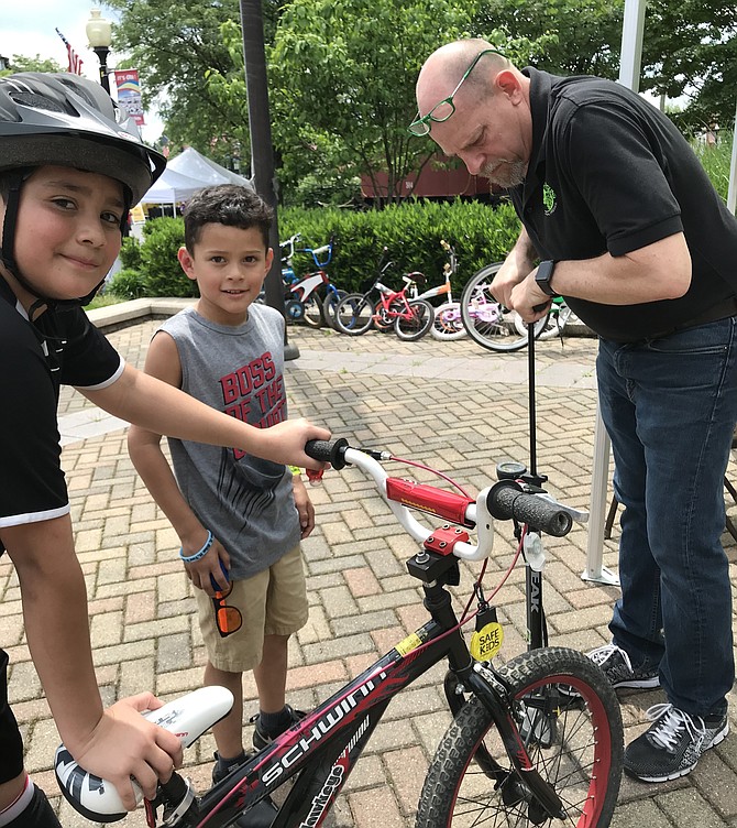 Volunteer Dave Meyer, co-owner of Green Lizard Cycling in Herndon, pumps up the tire for Edvin Orellan, 6, of Herndon at “Play It Safe: Bike Rodeo and Safety Fair” presented by Herndon Parks and Recreation.