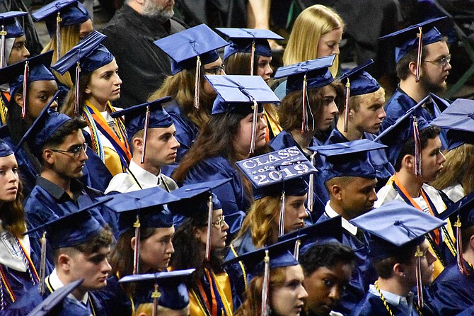 An embellished graduation cap sticks out in a sea of blue.