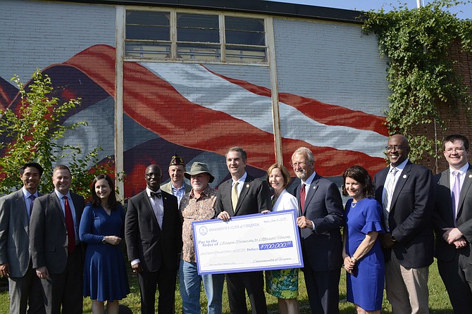 State and local officials hold up the representative $700,000 check for the new veterans’ housing project on Washington Blvd. From left: Kevin Yam, APAH board chair; Del. Patrick Hope, Katie Cristol, Arlington County Board; Carlos Hopkins, secretary of Veterans and Defense Affairs for the Commonwealth of Virginia; Bill Fahey and Dan Donahue, American Legion Post 139; Gov. Ralph Northam; Nina Janopaul, APAH president and CEO; John Milliken, APAH board member; state Sen. Barbara Favola; Christian Dorsey, Arlington County Board Chair; and Erik Johnston, director of the Department of Housing and Community Development for the Commonwealth of Virginia.