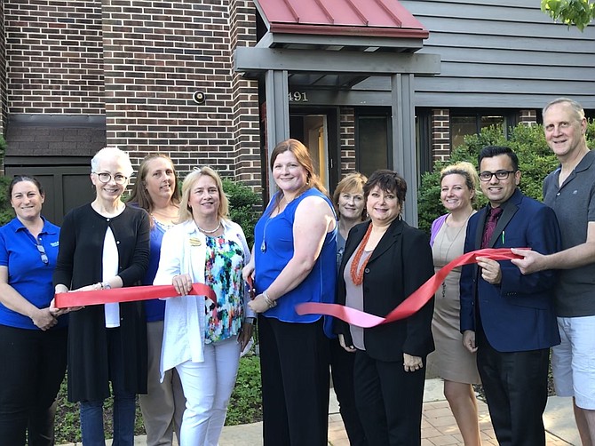 With a  snip of her large scissors, Casey White, C.E.O. and Founder of  White H.A.R.T. Massage (center) ceremonially opens her Holistic and Rehabilitation Therapy office in the Town of Herndon. Herndon Vice Mayor Sheila Olem (front center left), Councilmembers Signe Friedrichs and Pradip Dhakal (front center right), and others lend their support.