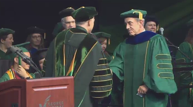 Alexandria Chief of Police Michael Brown, right, is awarded a doctorate degree in Criminology, Law and Society at the George Mason University 2019 spring commencement ceremony at Eagle Bank Arena.