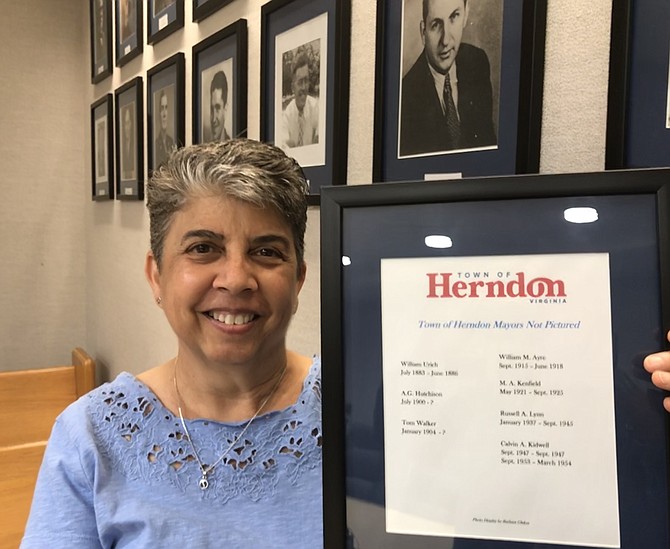 Town of Herndon resident Barbara A. Glakas shows the mayors' wall in the Hoover Conference Room adjacent to Town Chambers. Glakas is seeking help locating photos of seven mayors.